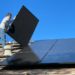 man installing solar panels on roof